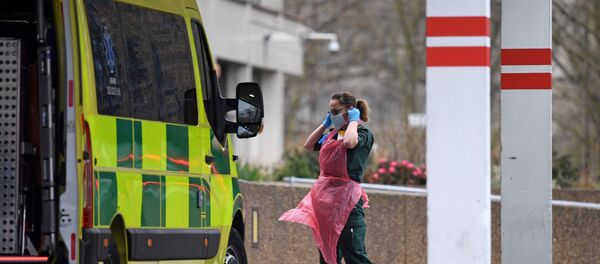 A member of staff wearing PPE of gloves, an apron and a face mask as a precautionary measure against COVID-19, prepares to disinfect an ambulance after it arrived with a patient at St Thomas' Hospital in north London, on April 1, 2020, as life in Britain continues during the nationwide lockdown to combat the novel coronavirus pandemic.  - Sputnik International