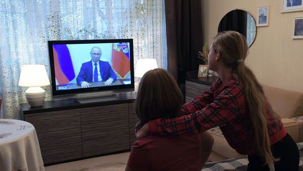 Russians watch President Putin's address on the COVID-19 situation from their apartment. - Sputnik International