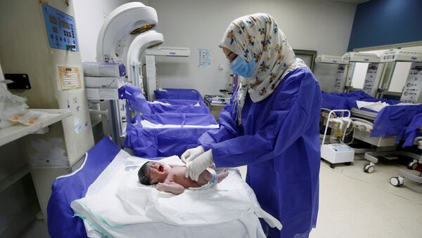 A nurse wearing a protective face mask and gloves to prevent the spread of coronavirus disease (COVID-19), takes care of a new born baby in a maternity room, in Najaf, Iraq April 2, 2020 - Sputnik International