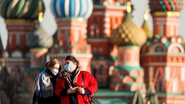 Women with protective masks, widely used as a preventive measure against coronavirus disease (COVID-19), walk across Red Square near the St. Basil's Cathedral in central Moscow, Russia March 26, 2020 - Sputnik International