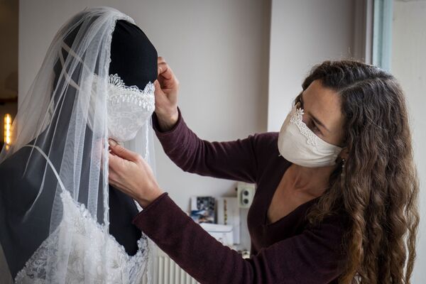 Wedding dress and evening wear designer Friederike Jorzig adjusts a mannequin wearing a wedding dress with matching protective mask in her store Chiton in Berlin on March 31, 2020 as the Germany continue to battle the Covid-19 corona virus pandemic - Sputnik International