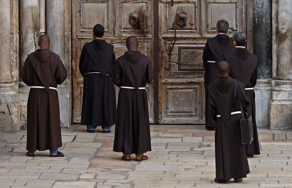 Franciscan monks pray in front of the closed door of the Church of the Holy Sepulchre, in the Christian quarter of the Old City of Jerusalem on March 27, 2020, during the novel coronavirus crisis against which Israel took strict measures - Sputnik International