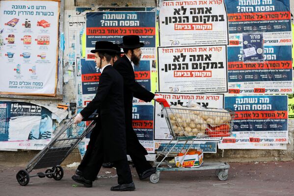 Ultra-Orthodox Jewish men push trolleys as they pass by billboards urging people to stay in their homes and keeping with government restrictions amid coronavirus disease (COVID-19) in Ashdod, Israel  April 1, 2020 - Sputnik International