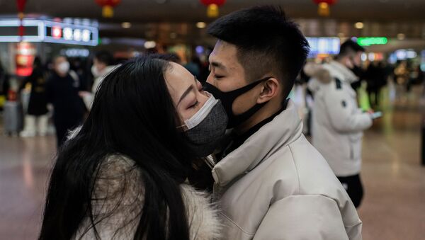 A couple, wearing protective masks, kisses goodbye as they travel for the Lunar New Year holidays, at Beijing West Railway Station in Beijing on January 24, 2020 - Sputnik International