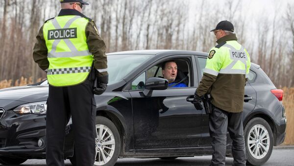 Surete du Quebec police officers talk to a driver as they set up a checkpoint for drivers approaching the province from neighbouring Ontario to enforce coronavirus disease (COVID-19) restrictions near Saint-Zotique, Quebec, Canada April 1, 2020 - Sputnik International