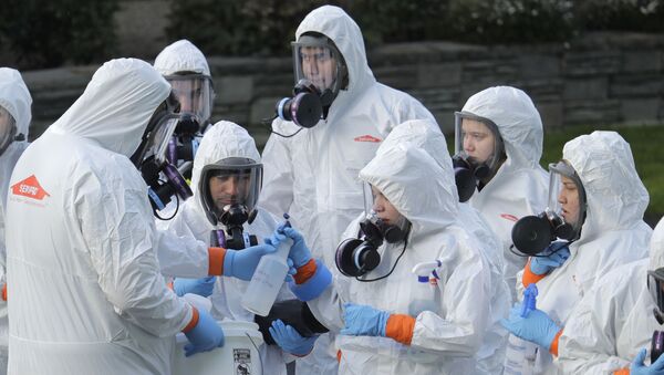 Workers from a Servpro disaster recovery team wearing protective suits and respirators are given supplies as they line up before entering the Life Care Center in Kirkland, Wash., to begin cleaning and disinfecting the facility, Wednesday, March 11, 2020 - Sputnik International