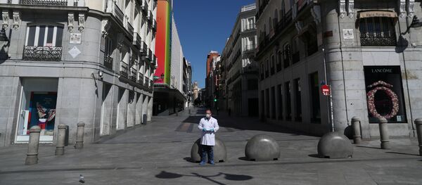 A pharmacist in protective gear stands in a deserted Puerta del Sol square A pharmacist in protective gear stands in a deserted Puerta del Sol square - Sputnik International