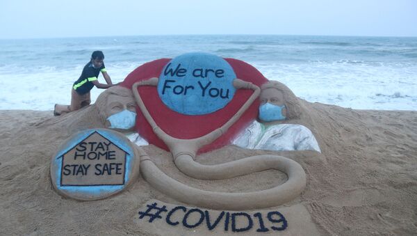 Indian artist Sudarsan Pattnaik puts some final touches as he makes a sand sculpture depicting doctors wearing protective facemasks with a message reading We are For You, Stay Home Stay Safe at Puri beach in Puri on April 3, 2020.  - Sputnik International