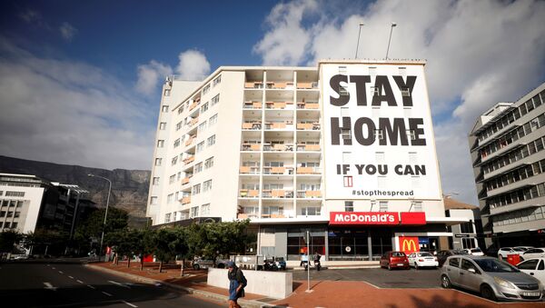 A man walks past a poster covering the side of a building ahead of a 21 day lockdown aimed at limiting the spread of coronavirus disease (COVID-19), in Cape Town - Sputnik International