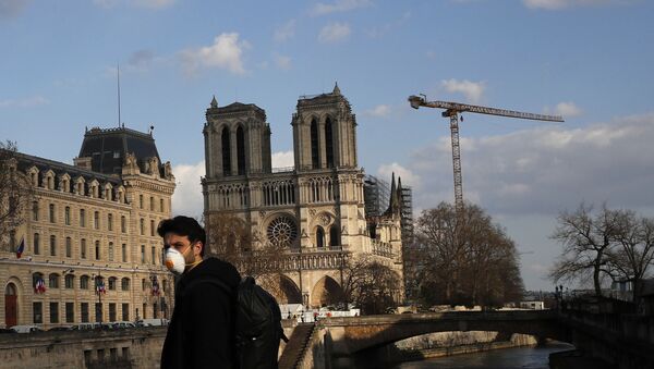 A masked man walks next to Notre Dame Cathedral, in Paris, Wednesday, March 18, 2020. - Sputnik International
