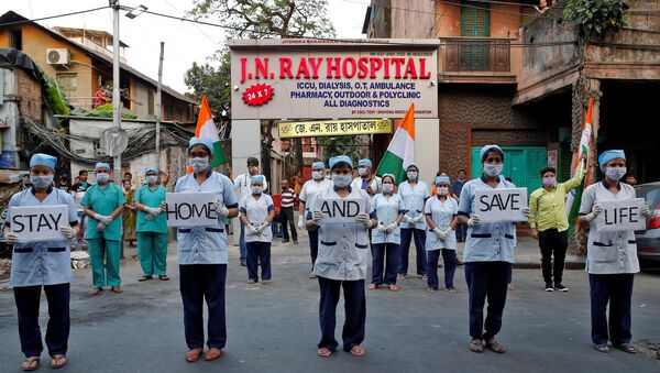 Medical staff members hold placards as they stand outside a hospital to show solidarity with people who are affected by the coronavirus disease (COVID-19), and with doctors, nurses and other healthcare workers from all over the world during a 21-day nationwide lockdown to slow the spreading of the disease, in Kolkata, India, April 5, 2020. - Sputnik International