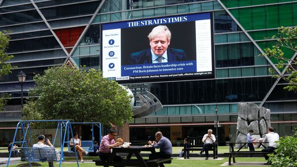 Workers take their lunch outdoors as a screen giving information about British Prime Minister Boris Johnson is seen on the background on the first day of circuit breaker measures to curb coronavirus (COVID-19) at the central business district in Singapore, April 7, 2020 - Sputnik International