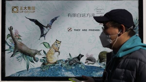 A man wearing a protective face mask walks by a propaganda poster promoting to protect wildlife animals after authorities crackdowns on wild animal markets following the coronavirus outbreak in Beijing, Wednesday, March 11, 2020. - Sputnik International