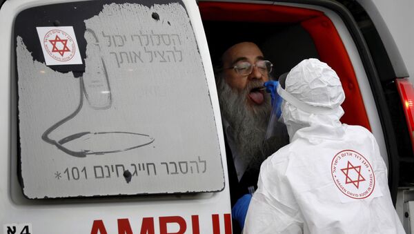 An Israeli medical worker wearing protective gear takes a swab from an ultra-Orthodox Jewish man for a coronavirus test, as part of the government's measures to stop the spread of the virus, in the Orthodox city of Bnei Brak, a suburb of Tel Aviv, Israel, Tuesday, March 31, 2020 - Sputnik International