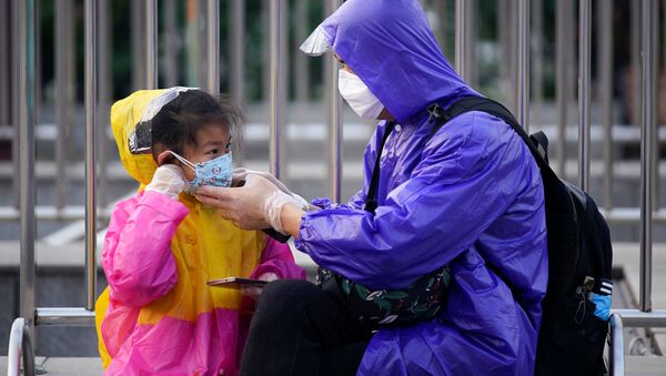 A person helps a child put on a protective face mask at Wuhan's Hankou Railway Station - Sputnik International