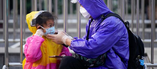 A person helps a child put on a protective face mask at Wuhan's Hankou Railway Station A person helps a child put on a protective face mask at Wuhan's Hankou Railway Station - Sputnik International