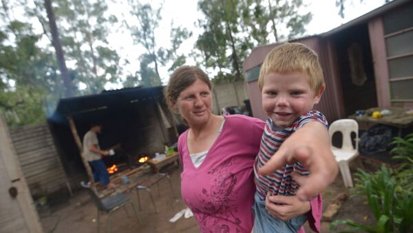 Marinda Labuschagne and her boy stand in front of their home with her husband cooking in the kitchen on a wood fire at a squatter camp for poor white South Africans at Coronation Park in Krugersdorp, on December 12, 2013 - Sputnik International