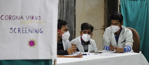 Indian doctors wait in an area set aside for possible COVID-19 patients at a free screening camp at a government run homeopathic hospital in New Delhi, India, Friday, March 13, 2020 - Sputnik International