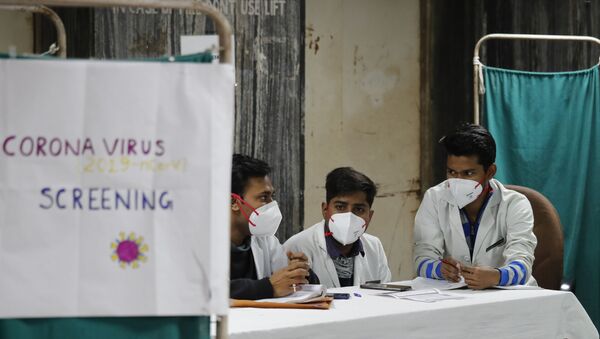 Indian doctors wait in an area set aside for possible COVID-19 patients at a free screening camp at a government run homeopathic hospital in New Delhi, India, Friday, March 13, 2020 - Sputnik International
