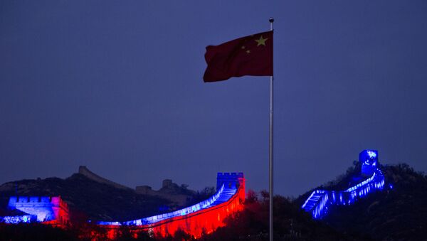 The Chinese national flag flies near a section of the Great Wall of China prepared to be lit by blue light to commemorate the 70th anniversary of the United Nations on the outskirts of Beijing, 24 October 2015. More than 200 iconic monuments, buildings, museums, bridges and other landmarks around the world were lighted up with blue - the official colour of the United Nations, to mark its 70th anniversary. - Sputnik International