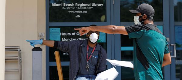 A man speaks with a library worker after receiving an unemployment form, as the outbreak of coronavirus disease (COVID-19) continues, in Miami Beach, Florida, U.S., April 8, 2020 A man speaks with a library worker after receiving an unemployment form, as the outbreak of coronavirus disease (COVID-19) continues, in Miami Beach, Florida, U.S., April 8, 2020 - Sputnik International