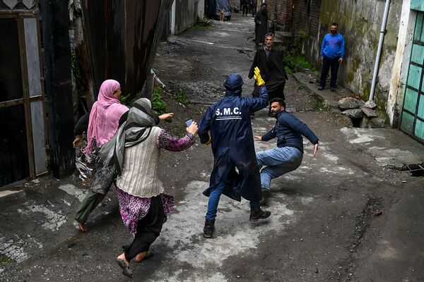 Local residents start a fight with a municipal worker (C) as they allegedly accuse him of not having sanitised properly their house at a residential area declared Red Zone for coronavirus by authorities during a government-imposed nationwide lockdown as a preventive measure against the COVID-19 coronavirus, in Srinagar on April 8, 2020.  - Sputnik International