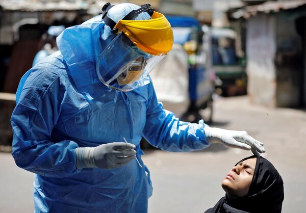 A doctor wearing a protective gear prepares to take a swab from a girl to test for the coronavirus disease (COVID-19) at a residential area in Ahmedabad, India, April 8, 2020. - Sputnik International
