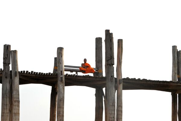 This picture taken on April 5, 2020 shows a monk sitting on U Bein Bridge in Mandalay.  - Sputnik International