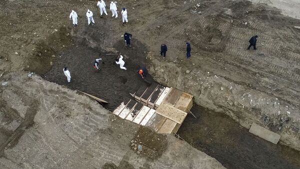 Workers wearing personal protective equipment bury bodies in a trench on Hart Island, Thursday, April 9, 2020, in the Bronx borough of New York. On Thursday, New York City’s medical examiner confirmed that the city has shortened the amount of time it will hold on to remains to 14 days from 30 days before they will be transferred for temporary internment at a City Cemetery. Earlier in the week, Mayor Bill DeBlasio said that officials have explored the possibility of temporary burials on Hart Island, a strip of land in Long Island Sound that has long served as the city’s potter’s field. - Sputnik International
