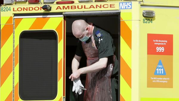 An ambulance worker puts gloves on outside St Thomas' Hospital in central London as British Prime Minister Boris Johnson is in intensive care fighting the coronavirus in London, Tuesday, April 7, 2020 - Sputnik International
