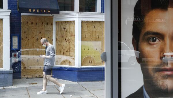 A man wearing a face mask to protect against the spread of the new coronavirus walks past a boarded-up restaurant in Washington, Thursday, April 9, 2020. - Sputnik International