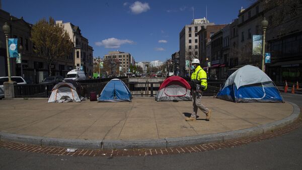 A street maintenance subcontractor for the District of Columbia walks past tents set up by the homeless on a sidewalk in Washington's Dupont Circle. - Sputnik International
