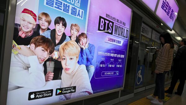 Passengers stand next to an advertisement for the role-playing game BTS World at a subway station in Seoul on June 25, 2019. - Sputnik International