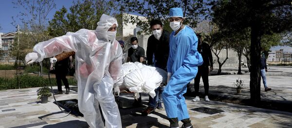 People wearing protective clothing carry the body of a victim who died after being infected with the new coronavirus at a cemetery just outside Tehran, Iran, Monday, March 30, 2020. - Sputnik International
