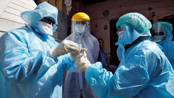 Doctors wearing protective gear seal a vial after taking a swab from a woman to test for coronavirus disease (COVID-19) at a residential area in Ahmedabad, India, April 9, 2020 - Sputnik International