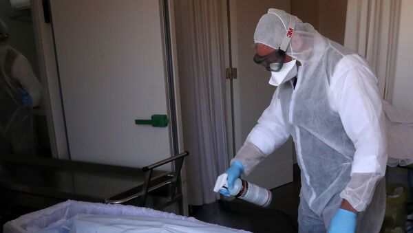 A mortuary worker sprays disinfectant on the body of a victim of the coronavirus disease (COVID-19), in Brussels, Belgium April 10, 2020 - Sputnik International