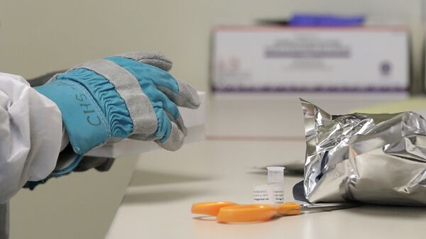 Pharmacist Michael Witte wears heavy gloves as he opens a frozen package of the potential vaccine for COVID-19, the disease caused by the new coronavirus, on the first day of a first-stage safety study clinical trial, Monday, March 16, 2020 - Sputnik International
