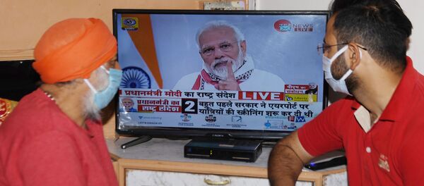 Residents wearing a facemasks watch on television Prime Minister Narendra Modi's address to the nation during a government-imposed nationwide lockdown as a preventive measure against the COVID-19 coronavirus, in Amritsar on April 14, 2020 - Sputnik International