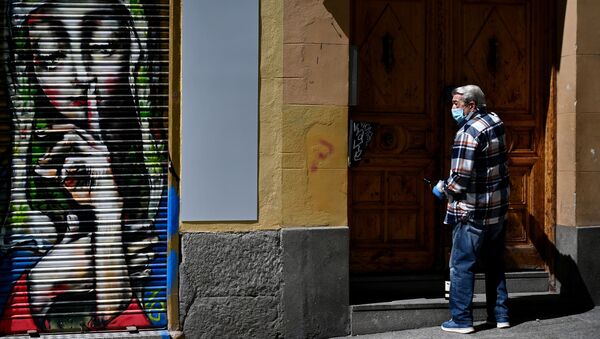 A man wearing a face mask opens the door of his building in Madrid - Sputnik International