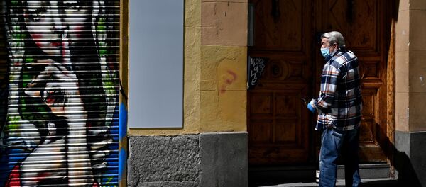 A man wearing a face mask opens the door of his building in Madrid - Sputnik International