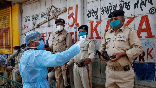 A paramedic uses an infrared thermometer to measure the temperature of a police officer alongside a road during a 21-day nationwide lockdown to slow the spreading of coronavirus disease (COVID-19) in Ahmedabad, India, 9 April 2020.  - Sputnik International
