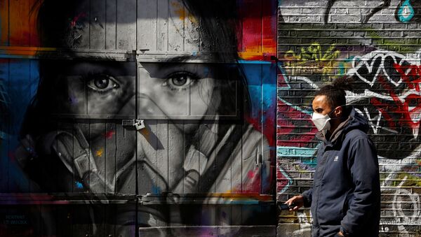 A man wearing a mask walks in Brick Lane in front of graffiti as the spread of the coronavirus disease (COVID-19) continues, London, Britain, April 14, 2020 - Sputnik International
