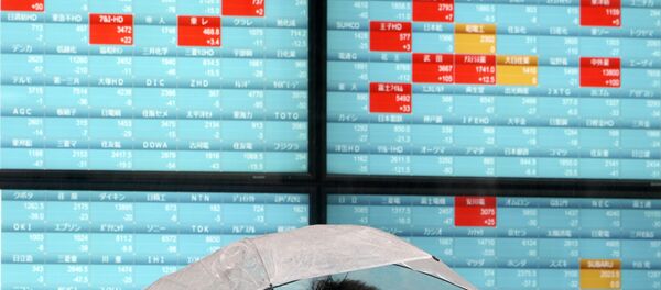 A man with a protective mask stands in the rain in front of an electronic stock board showing Japan's Nikkei 225 index at a securities firm in Tokyo Monday, April 13, 2020 - Sputnik International