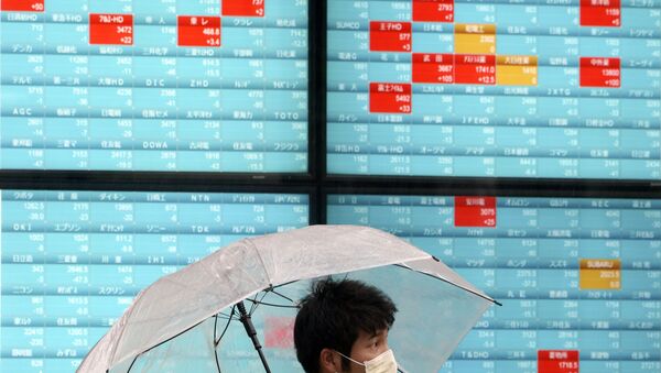 A man with a protective mask stands in the rain in front of an electronic stock board showing Japan's Nikkei 225 index at a securities firm in Tokyo Monday, April 13, 2020 - Sputnik International