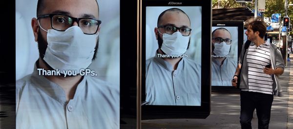 A man walks past bus stop advertising boards displaying thank you messages to health workers in response to the COVID-19 coronavirus outbreak, in Sydney on April 15, 2020 - Sputnik International