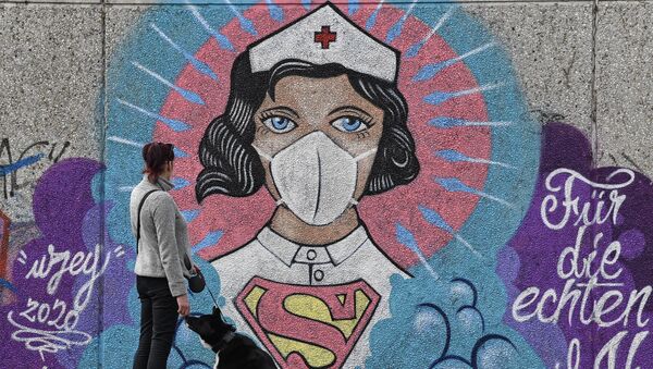 A woman watches a coronavirus graffiti by street artist 'Uzey' showing a nurse as Superwoman on a wall in Hamm, Germany, on Easter Monday, April 13, 2020 - Sputnik International
