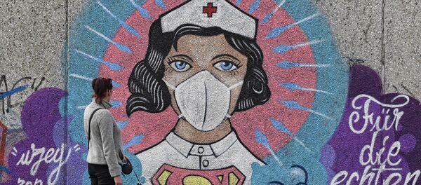 A woman watches a coronavirus graffiti by street artist 'Uzey' showing a nurse as Superwoman on a wall in Hamm, Germany, on Easter Monday, April 13, 2020 - Sputnik International