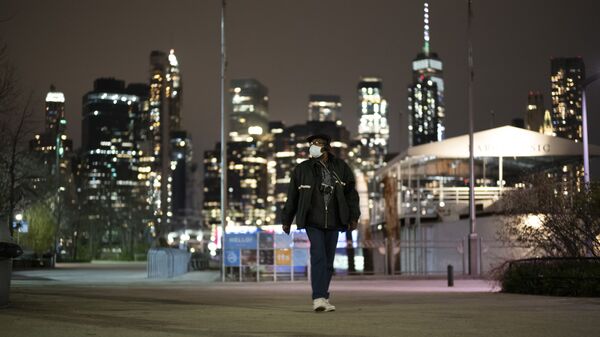 A man wearing a mask walks through Brooklyn Bridge Park, Tuesday night, April 14, 2020 during the coronavirus pandemic in New York. Known as The City That Never Sleeps, New York's streets are particularly empty during the pandemic. - Sputnik International