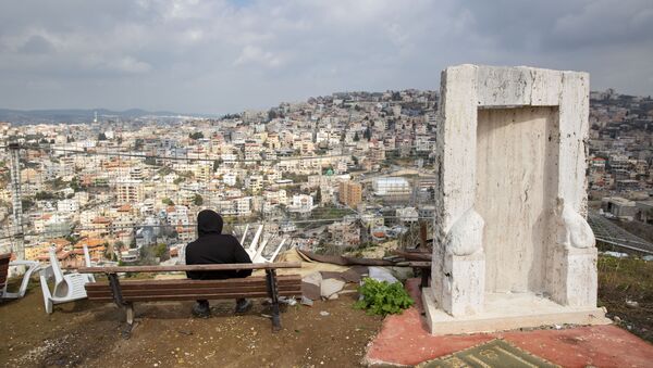 In this Tuesday, 4 Feb. 2020, photo, an Israeli Arab youth sits at a view point overlooking the Israeli Arab town of Umm al-Fahm. President Donald Trump's Mideast initiative suggests that a densely populated Arab region of Israel could be added to a future Palestinian state, if both sides agree. The proposal has infuriated many of Israel's Arab citizens, who view it as a form of forced transfer - Sputnik International