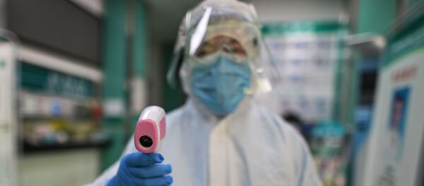 A medical worker prepares to check the temperature of an AFP photojournalist before a COVID-19 coronavirus test in Wuhan in China's central Hubei province on April 16, 2020.  - Sputnik International